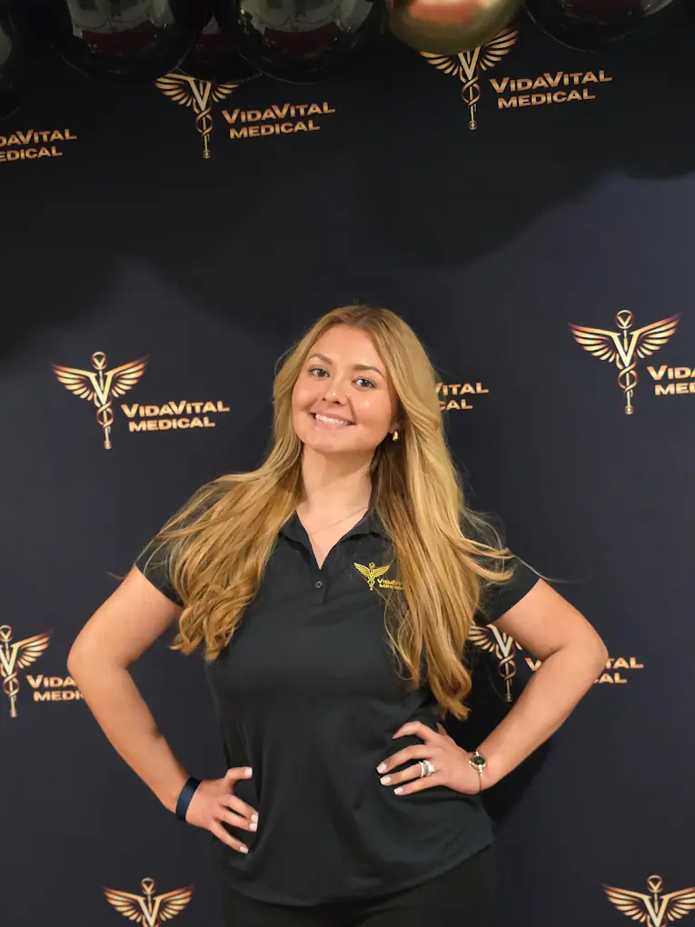 VidaVital Medical team member posing in front of the branded backdrop